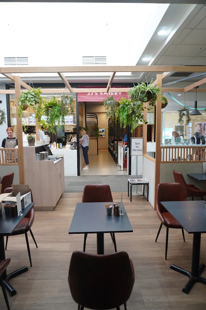 Warm dining area at JJ's Eatery with timber details and burgundy chairs