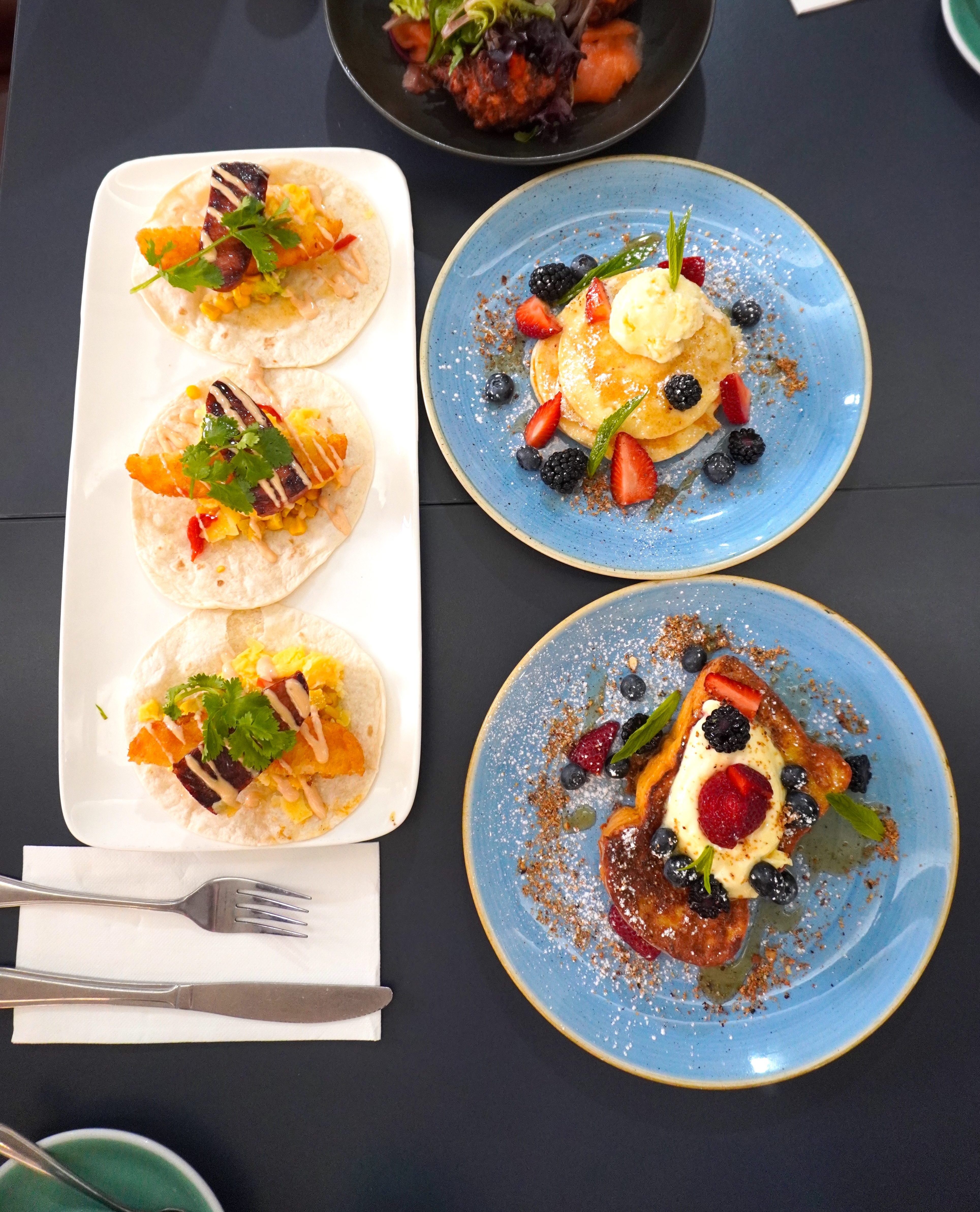 Breakfast dishes and tacos on a table at JJ's Eatery